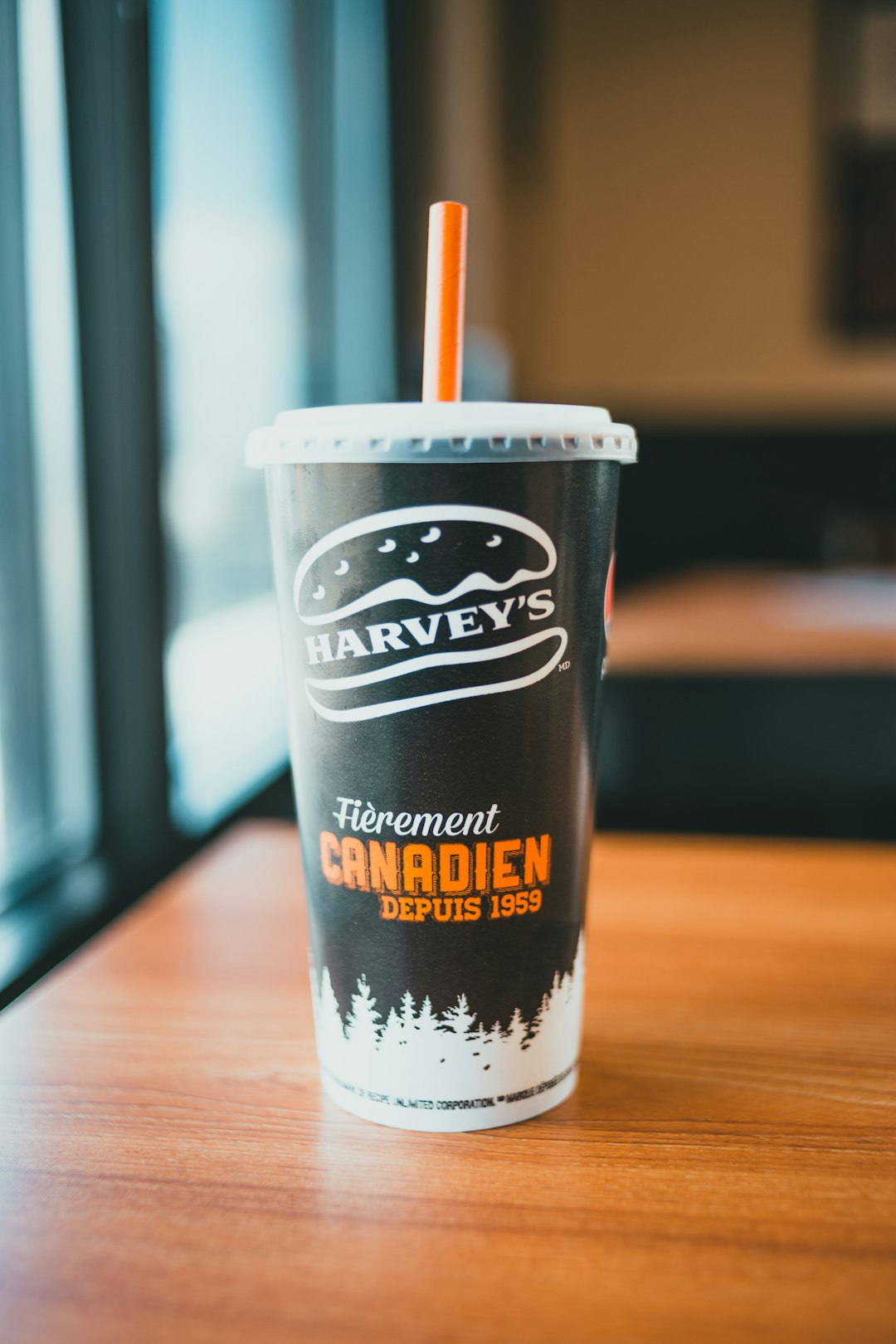 white and black disposable cup on brown wooden table