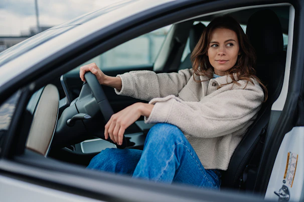 A female driver checking the car’s safety equipment before starting a trip, with a calm and professional demeanor.