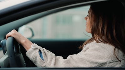 woman in gray hoodie sitting inside car during daytime