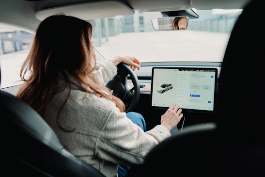 A driver using a tablet inside a car carrier truck, checking digital documents.