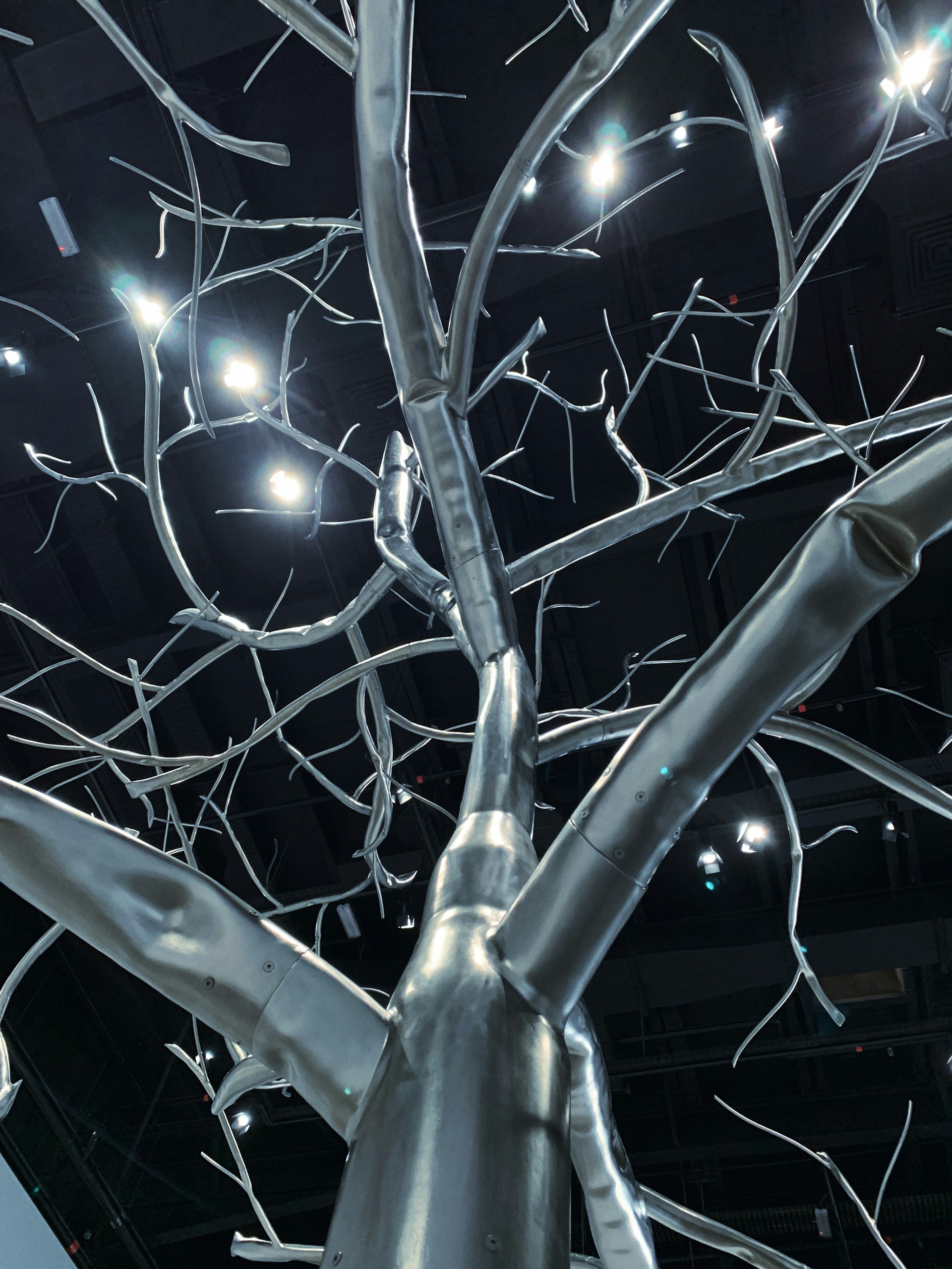 A striking sculpture blending metal and light, showcasing intricate technological details in a dark gallery setting.