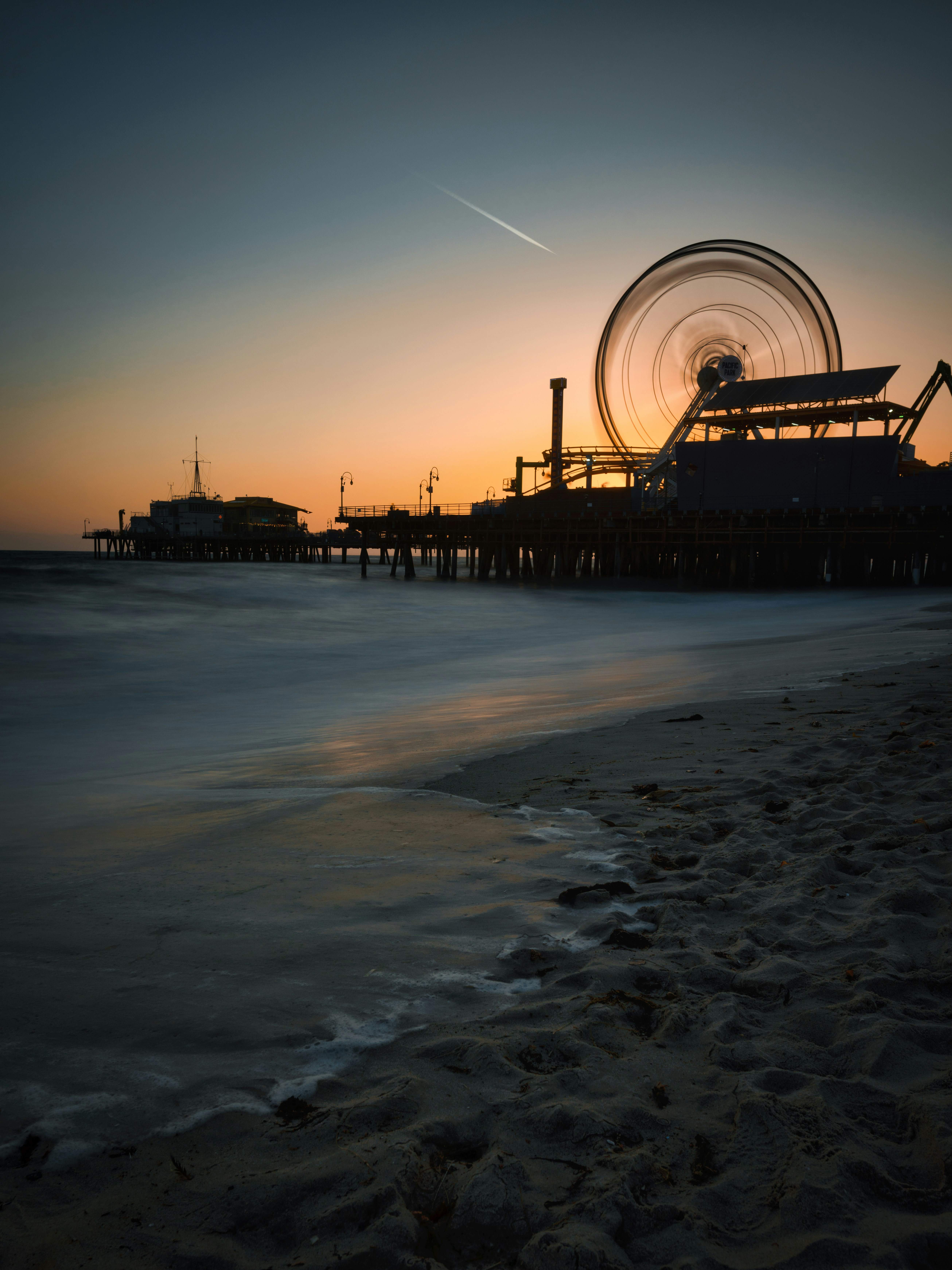 Gente caminando en la orilla de la playa durante la puesta del sol