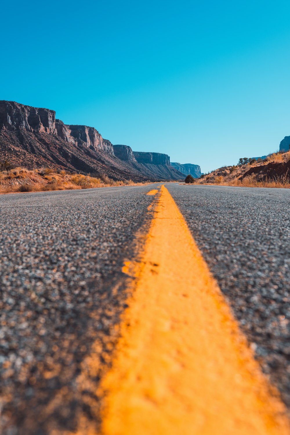 gray concrete road near brown rocky mountain during daytime