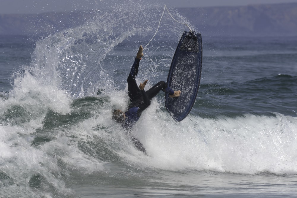 hombre con traje de neopreno negro montando en una tabla de surf negra durante el día
