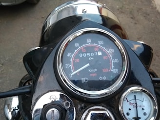 A close-up view of a motorcycle dashboard, featuring a speedometer with both kilometers and miles per hour, an odometer reading 507 kilometers, and an amp meter displaying the brand Royal Enfield.