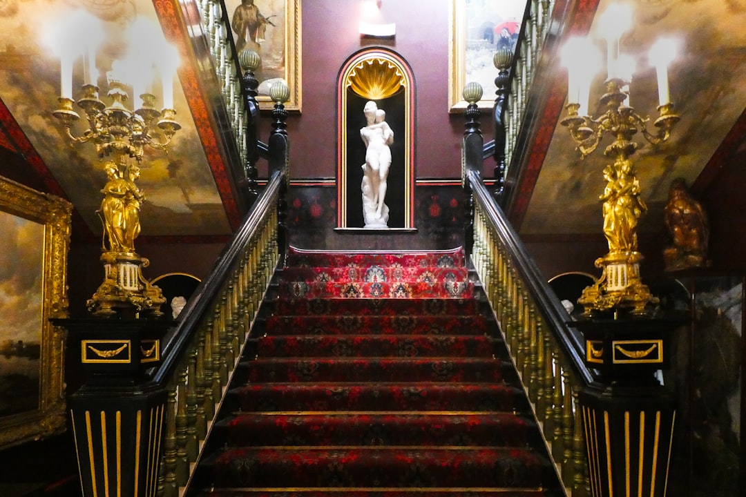 brown and white wooden staircase, Red carpeted stairs taken looking up.