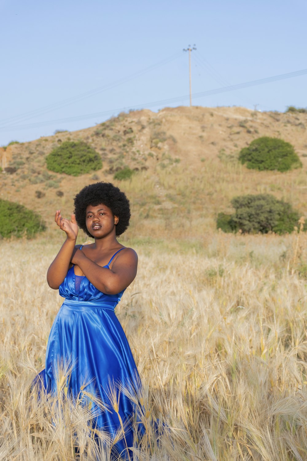 woman in blue spaghetti strap dress standing on brown grass field during daytime