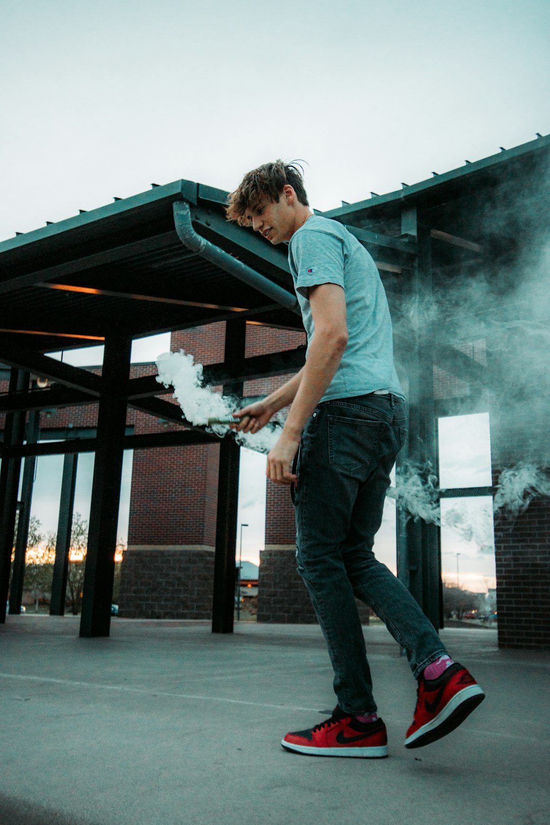 man in blue t-shirt and blue denim jeans holding white smoke