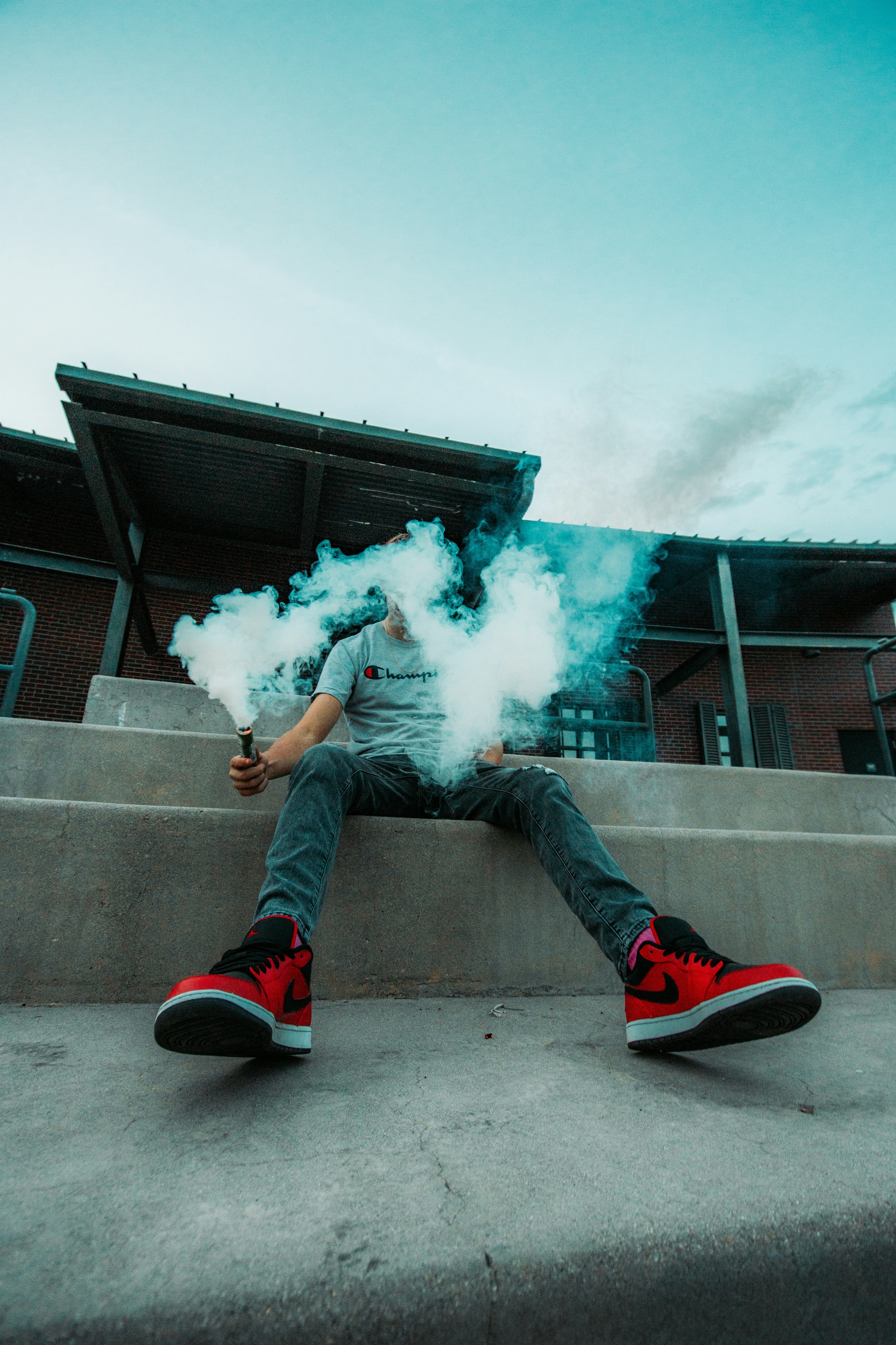 person in blue denim jeans and red nike sneakers smoking