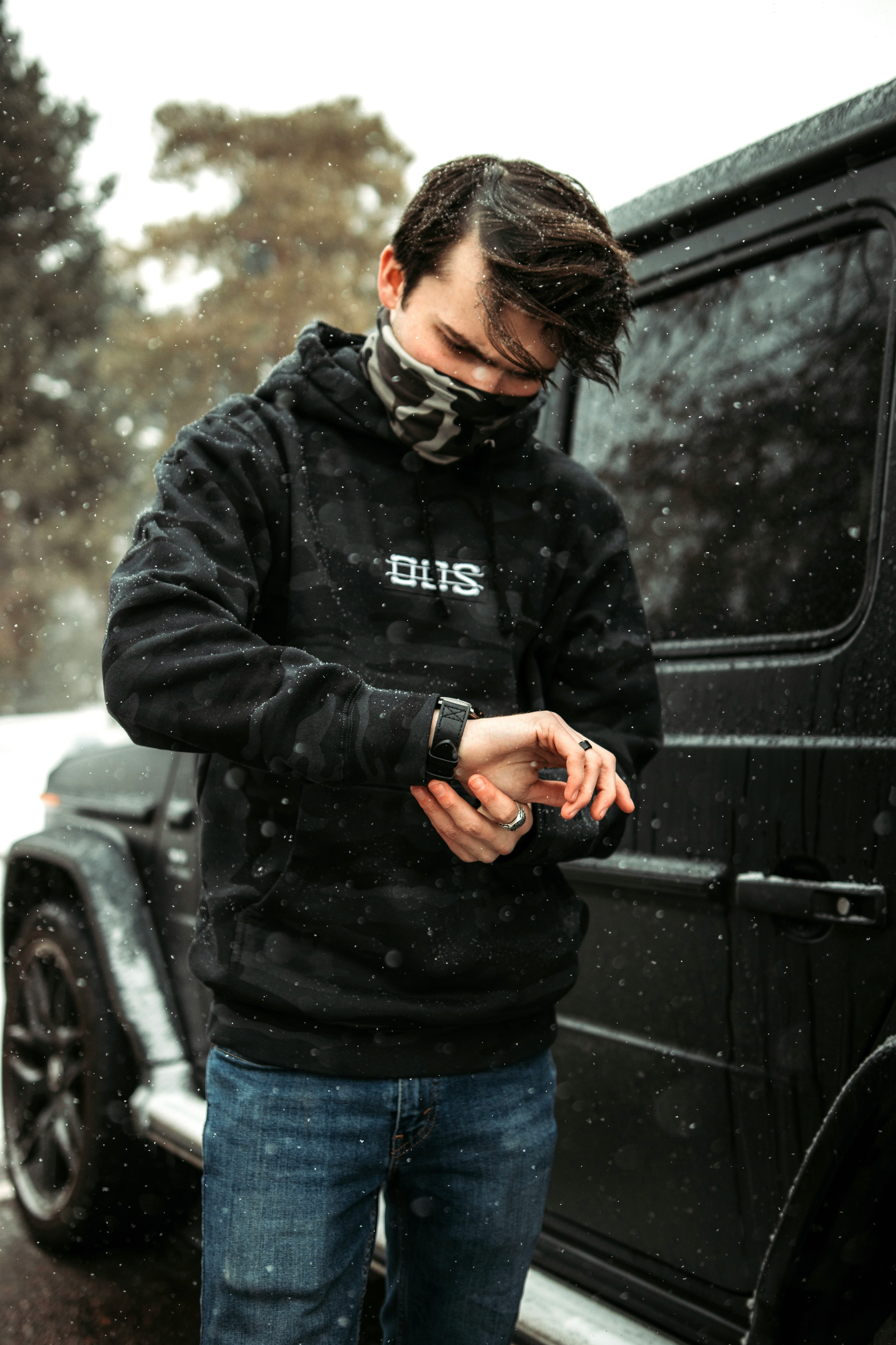 man in black leather jacket standing beside black car during daytime