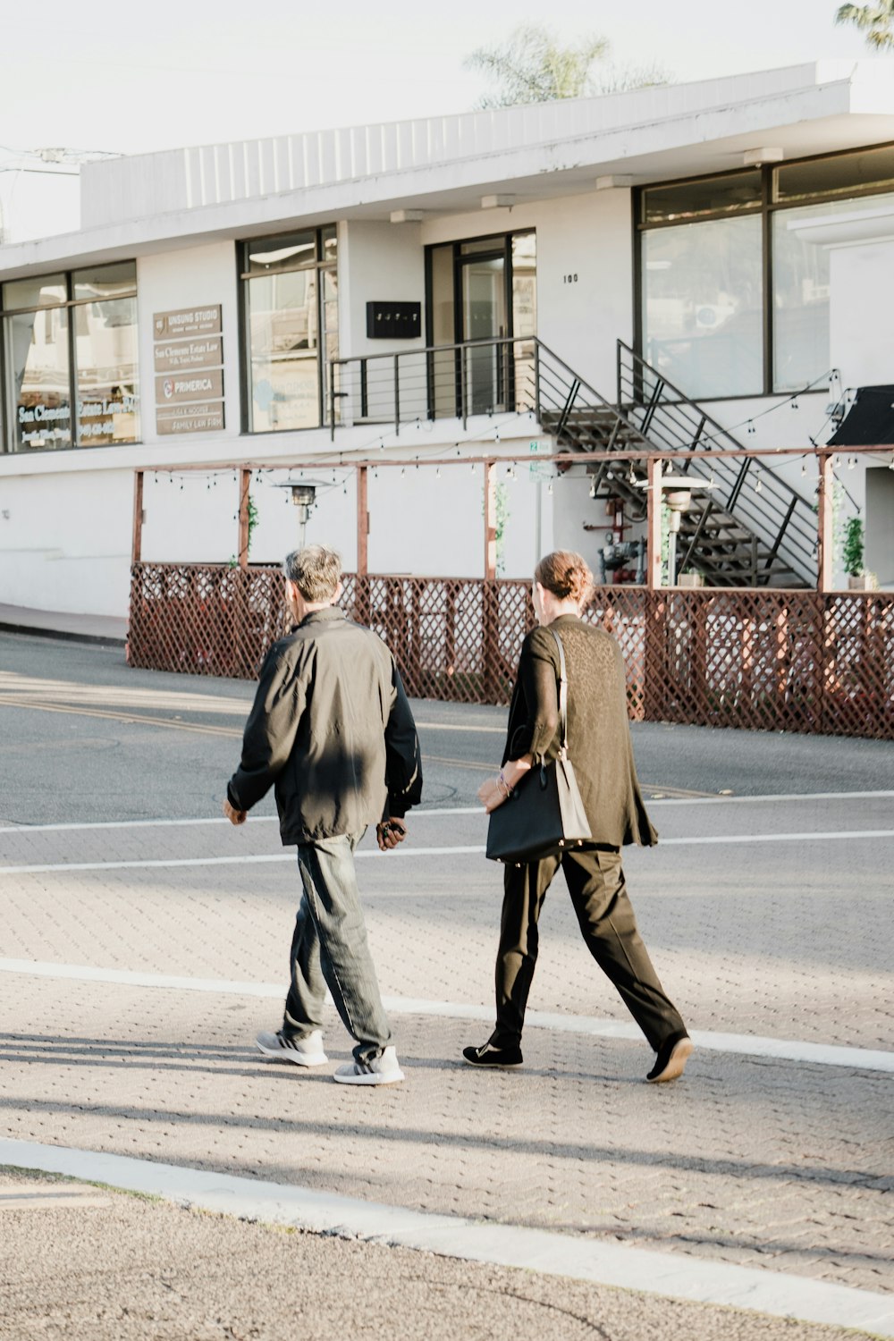 woman in black coat standing on sidewalk during daytime