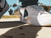 Photo of smiling person wearing a pair of stylish rubber shoes outside on a sunny day.