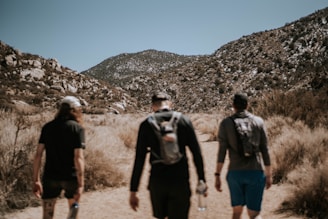 3 men walking on dirt road during daytime