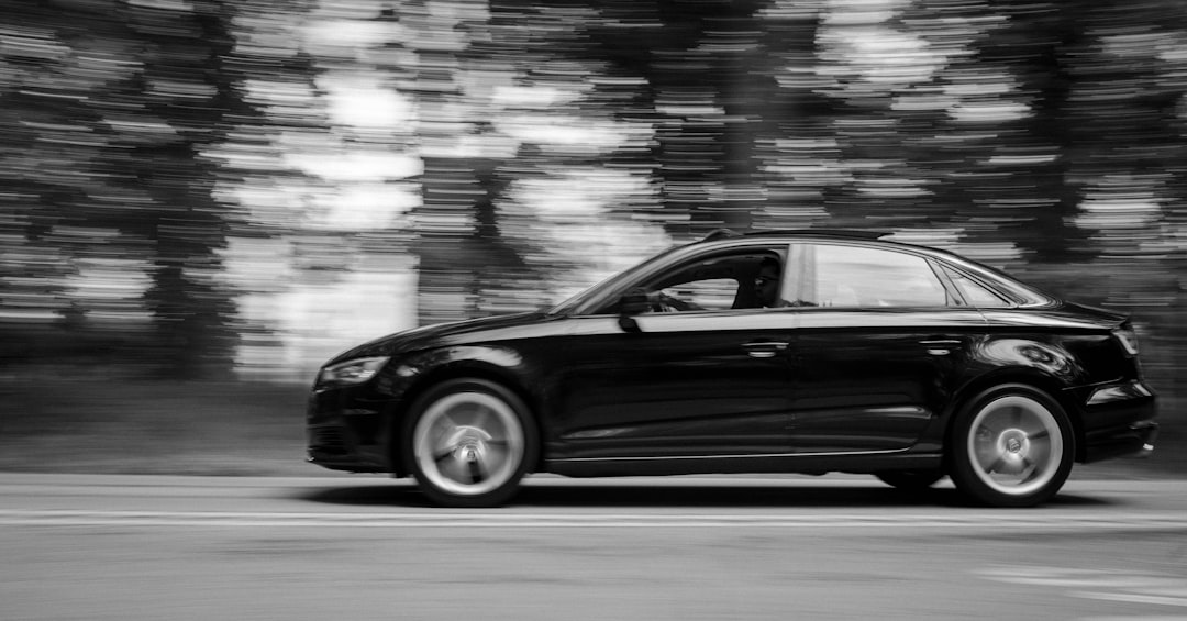 grayscale photo of black car on road