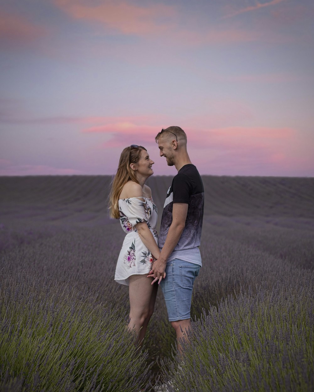 um homem e uma mulher em pé em um campo de lavanda