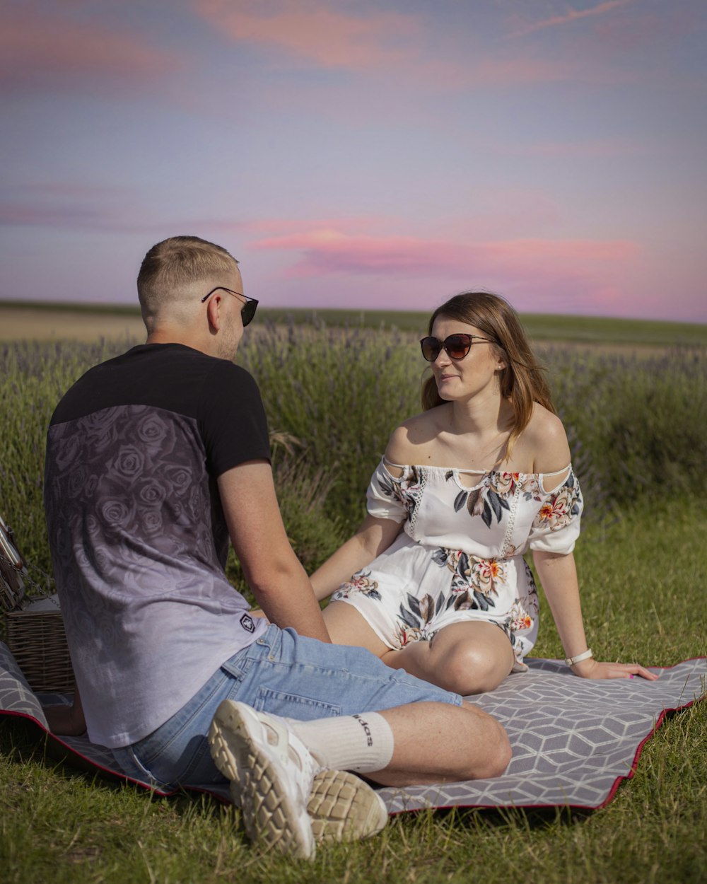 낮 동안 푸른 잔디밭에 빨간색과 흰색 직물에 앉아 있는 남자와 여자