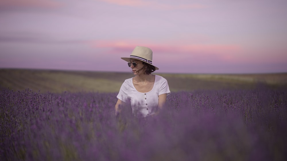 donna in camicia bianca e cappello marrone in piedi sul campo di erba verde durante il giorno