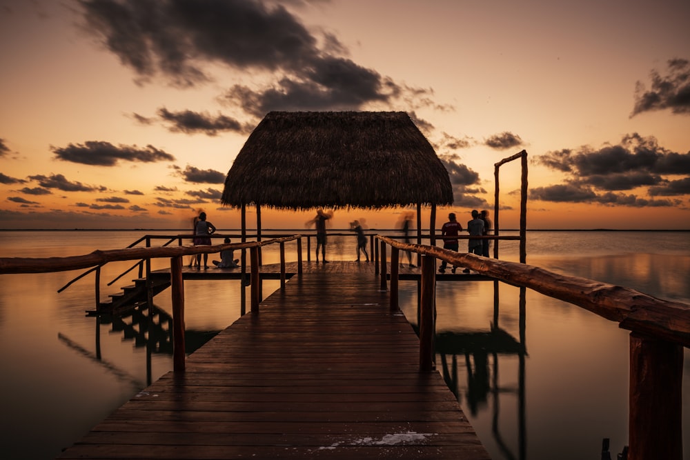 brown wooden dock on sea during sunset