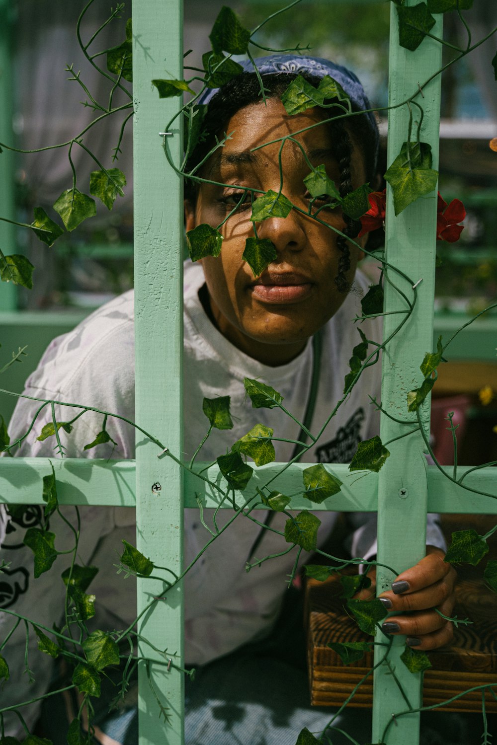 woman in white hijab standing behind green plant