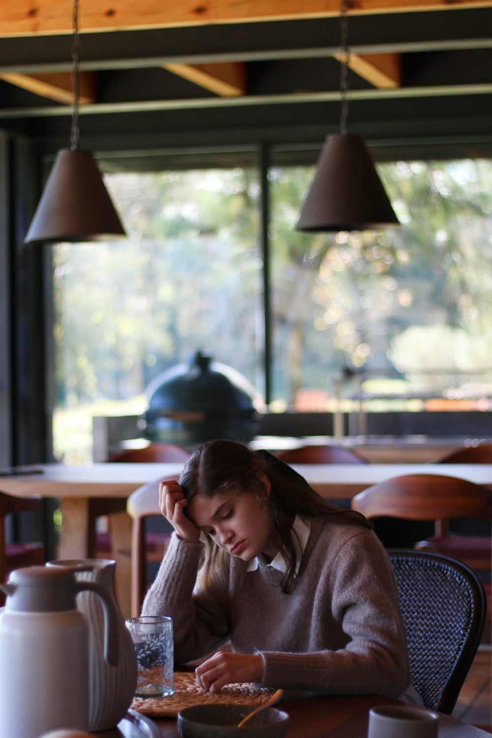 woman in gray long sleeve shirt sitting on brown wooden chair