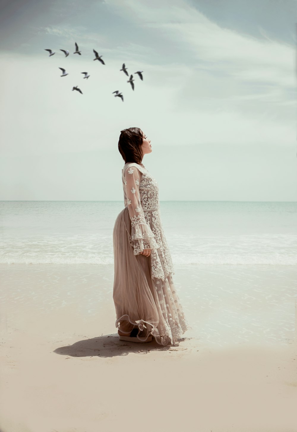 woman in white dress walking on beach during daytime