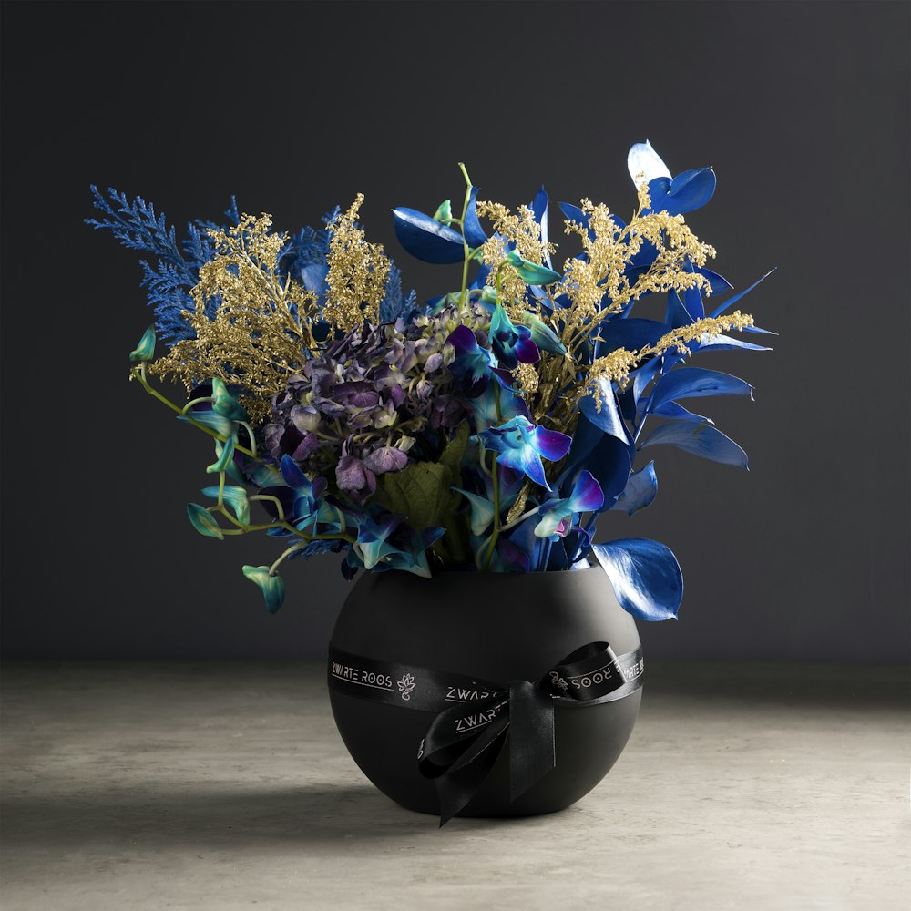 blue and yellow flowers on black vase