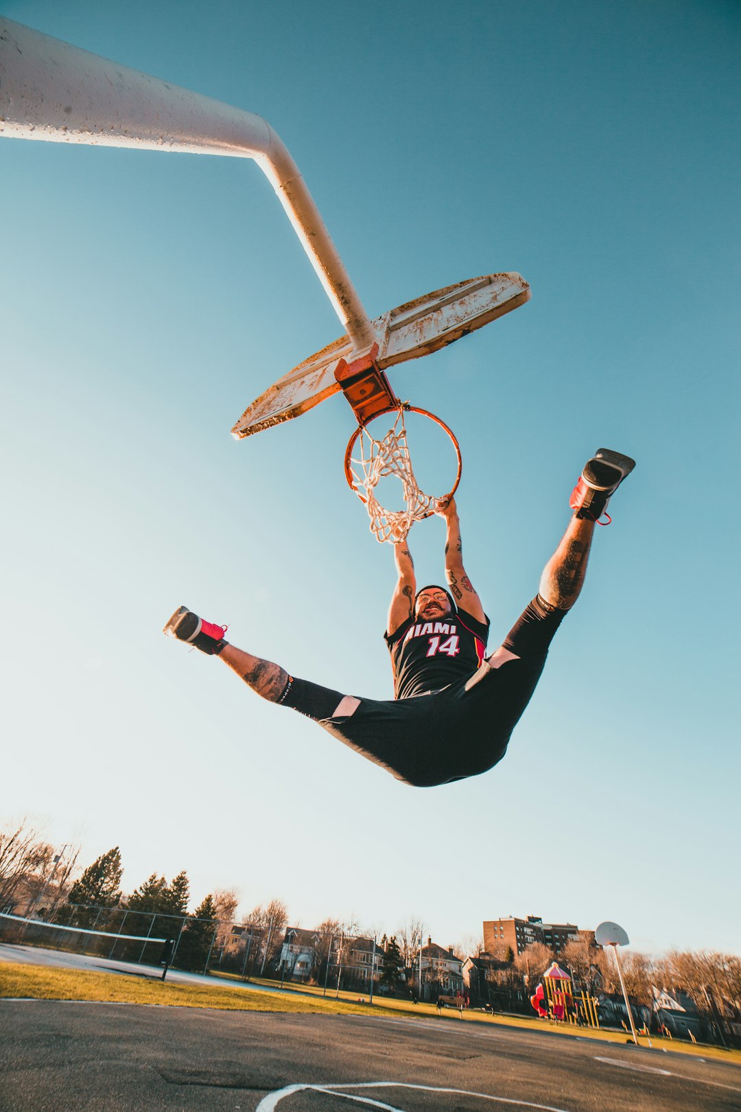 man in black and white jersey shirt and black pants riding on basketball hoop