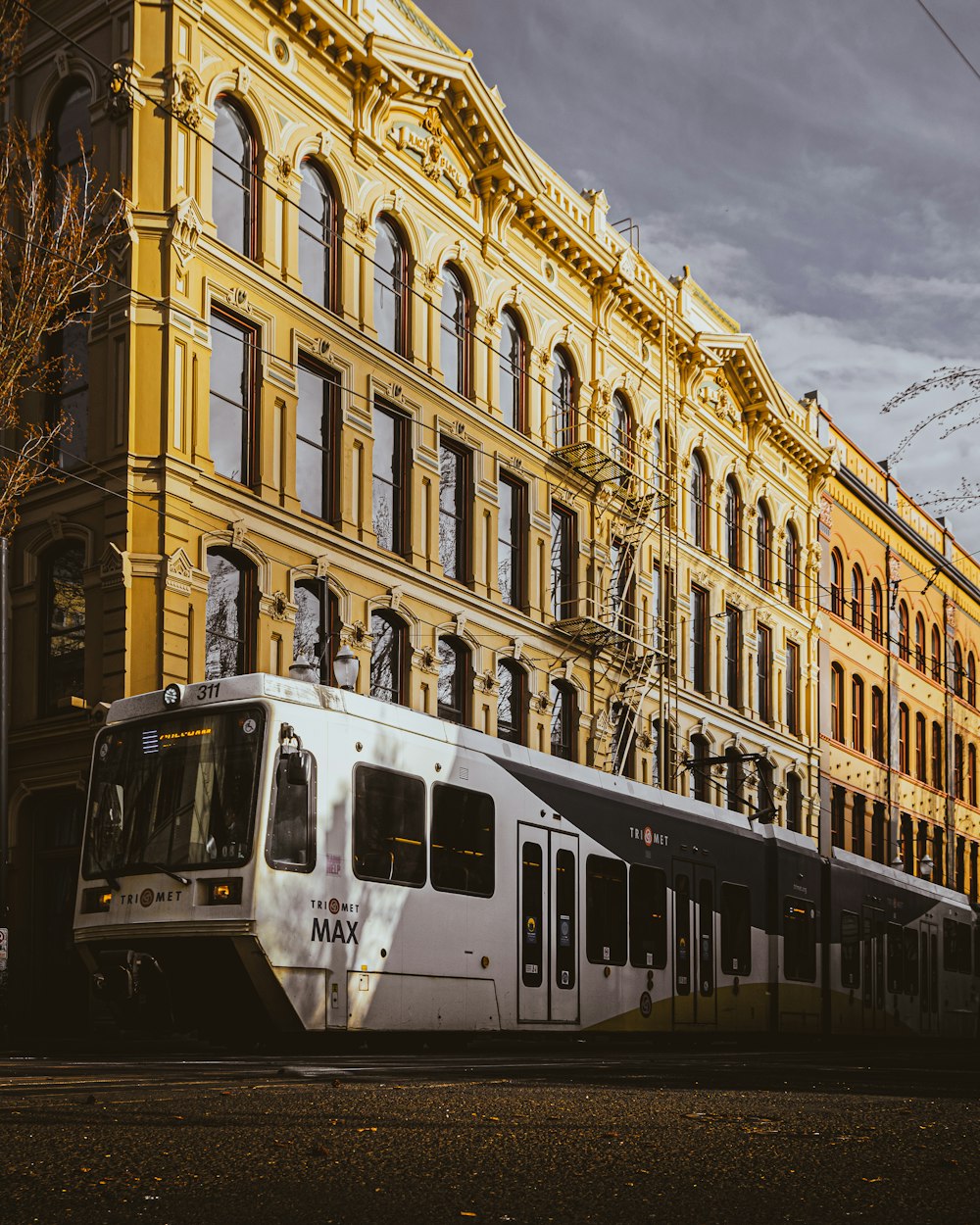 white and black train in front of beige concrete building