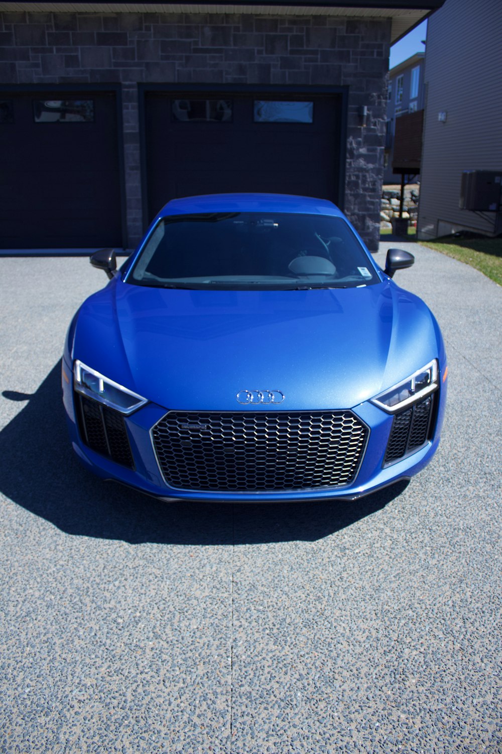 Audi R 8 bleue garée sur une route goudronnée grise pendant la journée