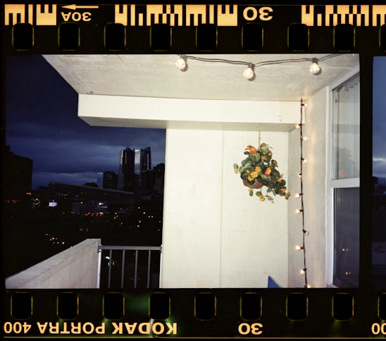 A modern balcony fitted with sleek invisible grills overlooking a vibrant cityscape at sunset.
