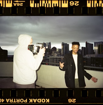 man in black suit standing beside man in white thobe