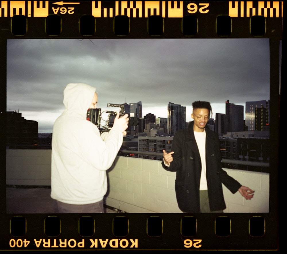 man in black suit standing beside man in white thobe