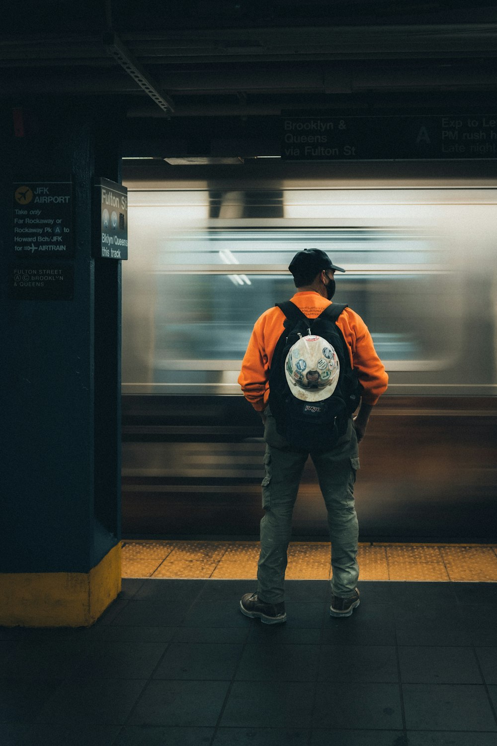 Hombre con chaqueta negra y jeans de mezclilla azul de pie en la estación de tren