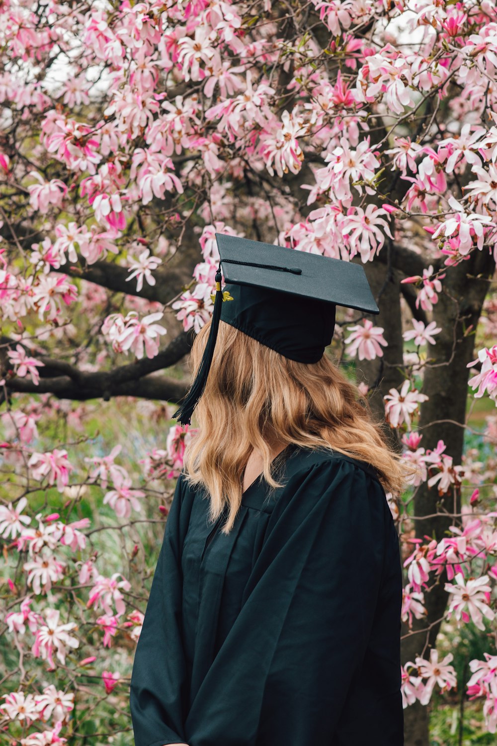 woman in black academic dress standing beside purple flowers