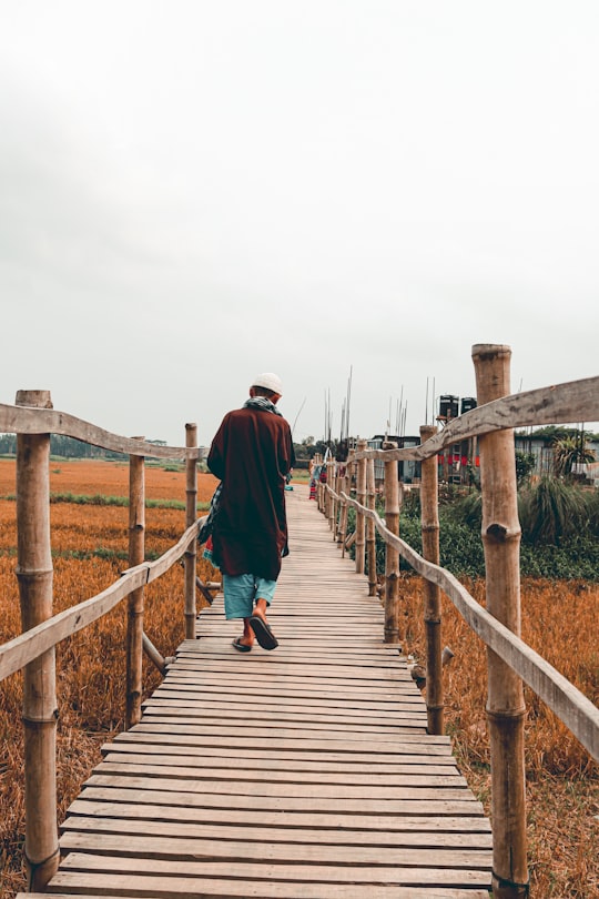 man in black jacket walking on wooden bridge during daytime in Munshiganj Bangladesh