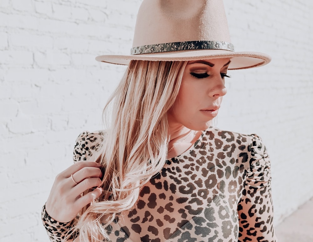 Mujer con camisa de manga larga con estampado de leopardo marrón y negro con sombrero beige