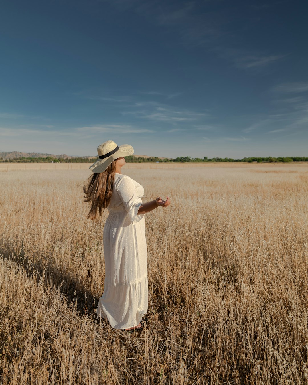 woman in white dress standing on brown grass field during daytime