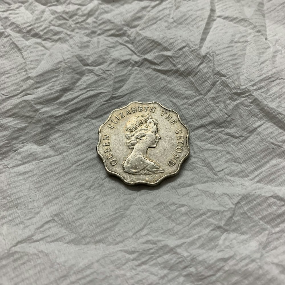 gold round coin on white textile