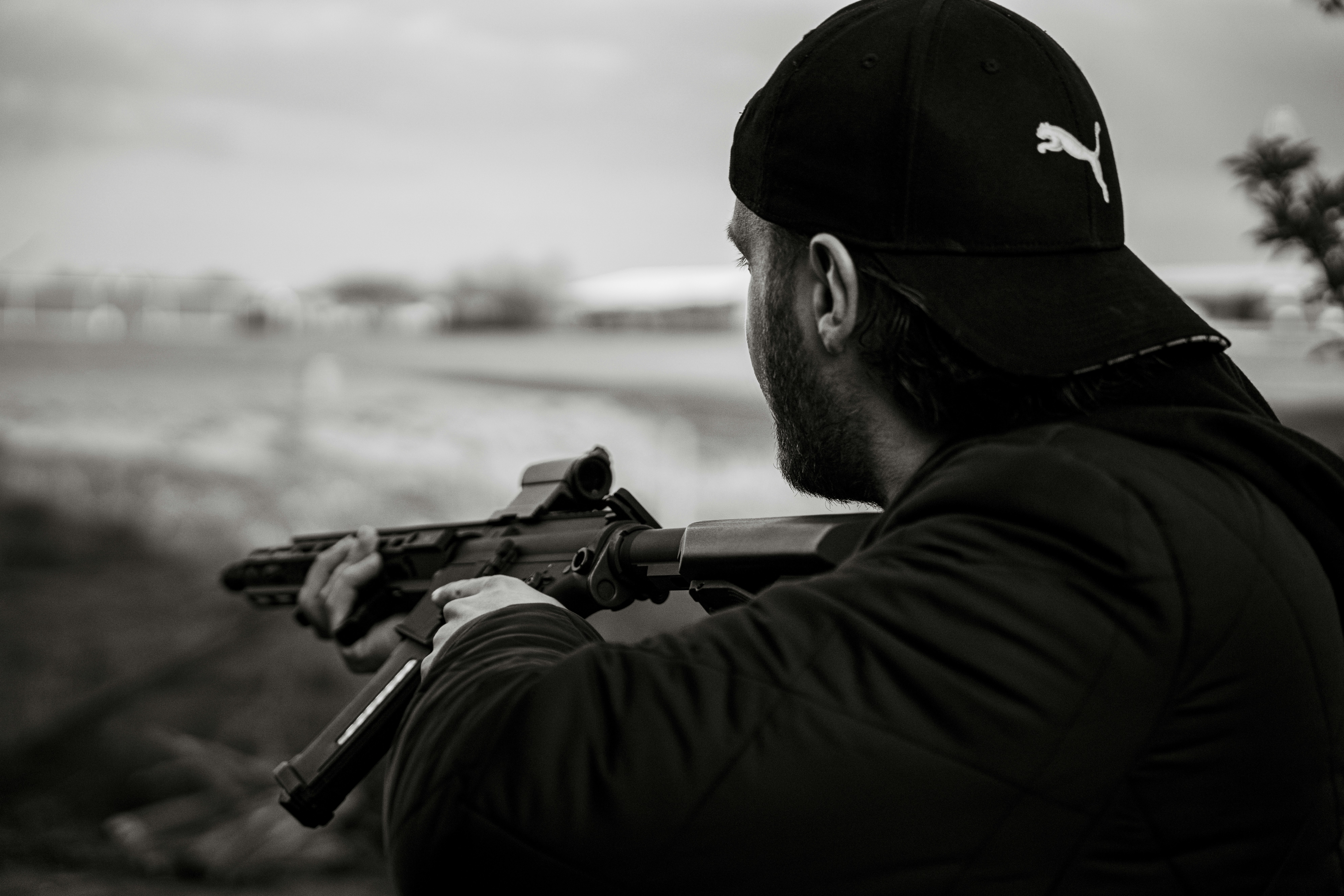 man in black fitted cap holding black rifle