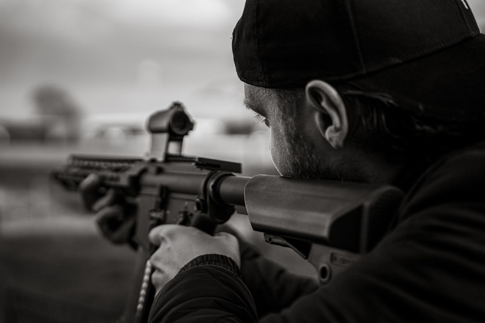 Hombre con gorra de punto negra sosteniendo rifle