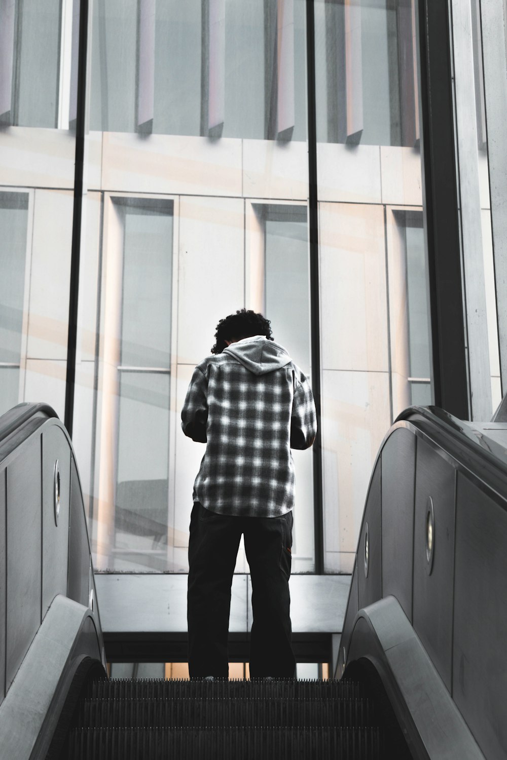 man in black and white plaid dress shirt standing in front of glass window