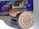 A stack of chocolate sandwich cookies with cream filling is prominently displayed, with a focus on the intricate logo and pattern on the top cookie. In the background, there is a partially visible blue and red package with an image of the cookies and nutritional information.