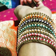 A hand adorned with multiple gold bangles against a neutral backdrop.