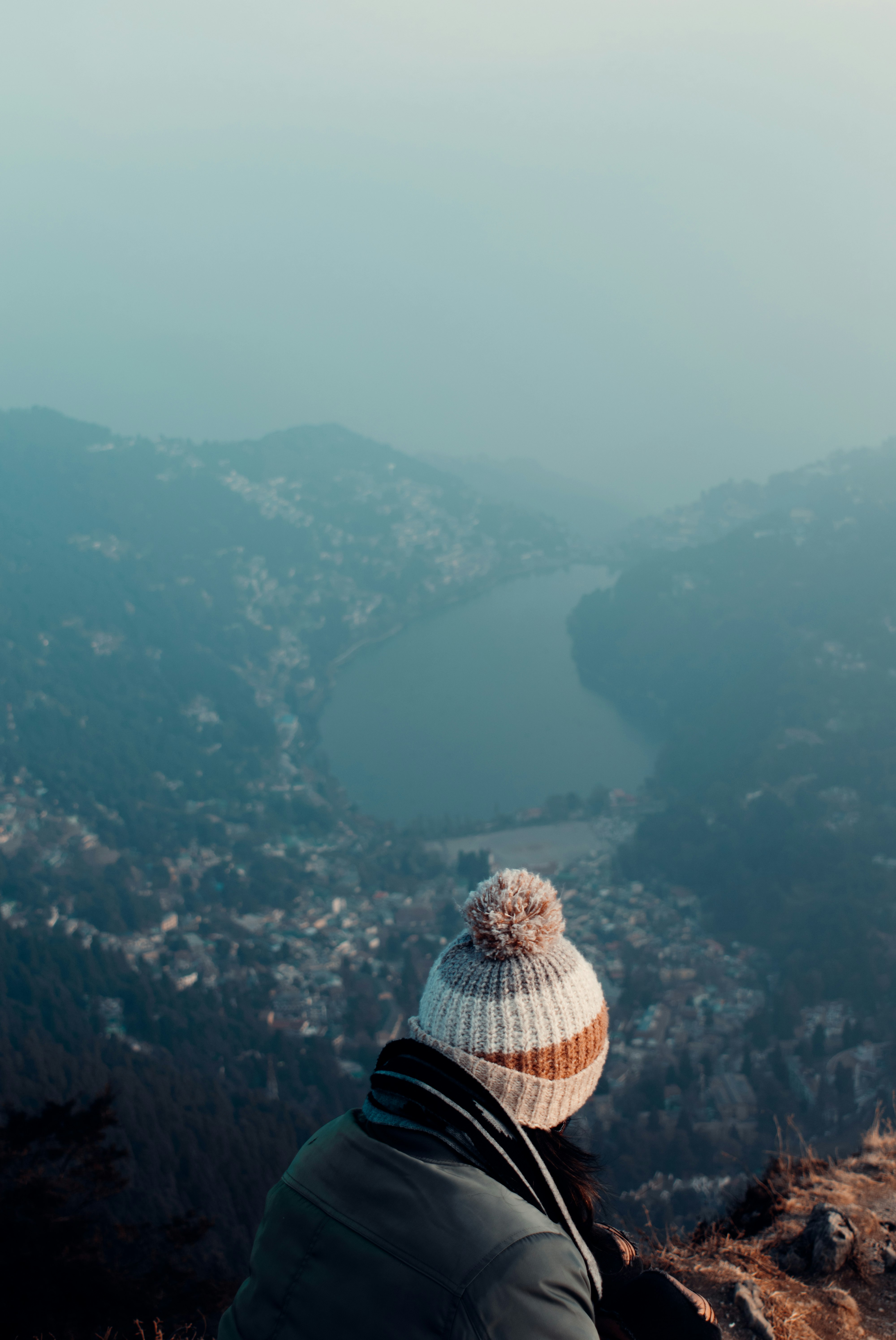 person in black jacket and brown and white plaid hat standing on top of the mountain