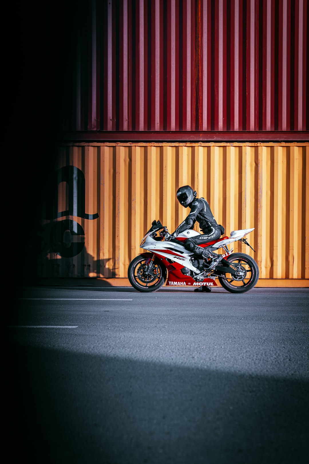 man in black jacket riding red and black sports bike