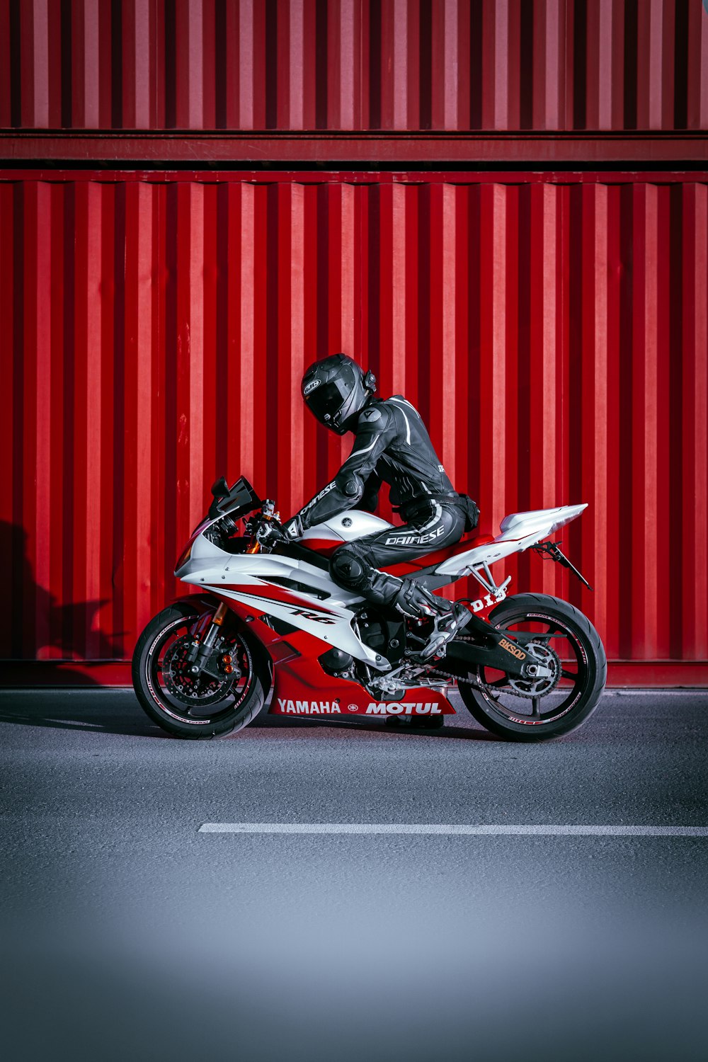 man in black jacket riding on red sports bike