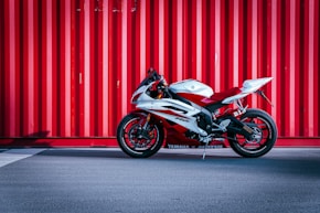 black and white sports bike parked beside red wall