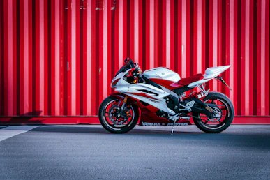 black and white sports bike parked beside red wall