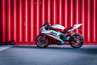 black and white sports bike parked beside red wall