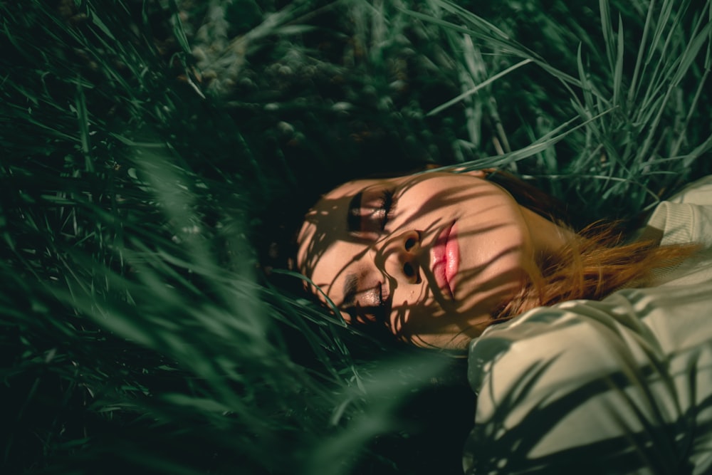 woman in white and black camouflage hoodie lying on green grass